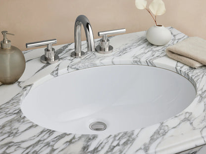 Chelsea Single Washstand with white marble top, oval ceramic sink, polished nickel frame, and clear glass shelf on a tiled floor.