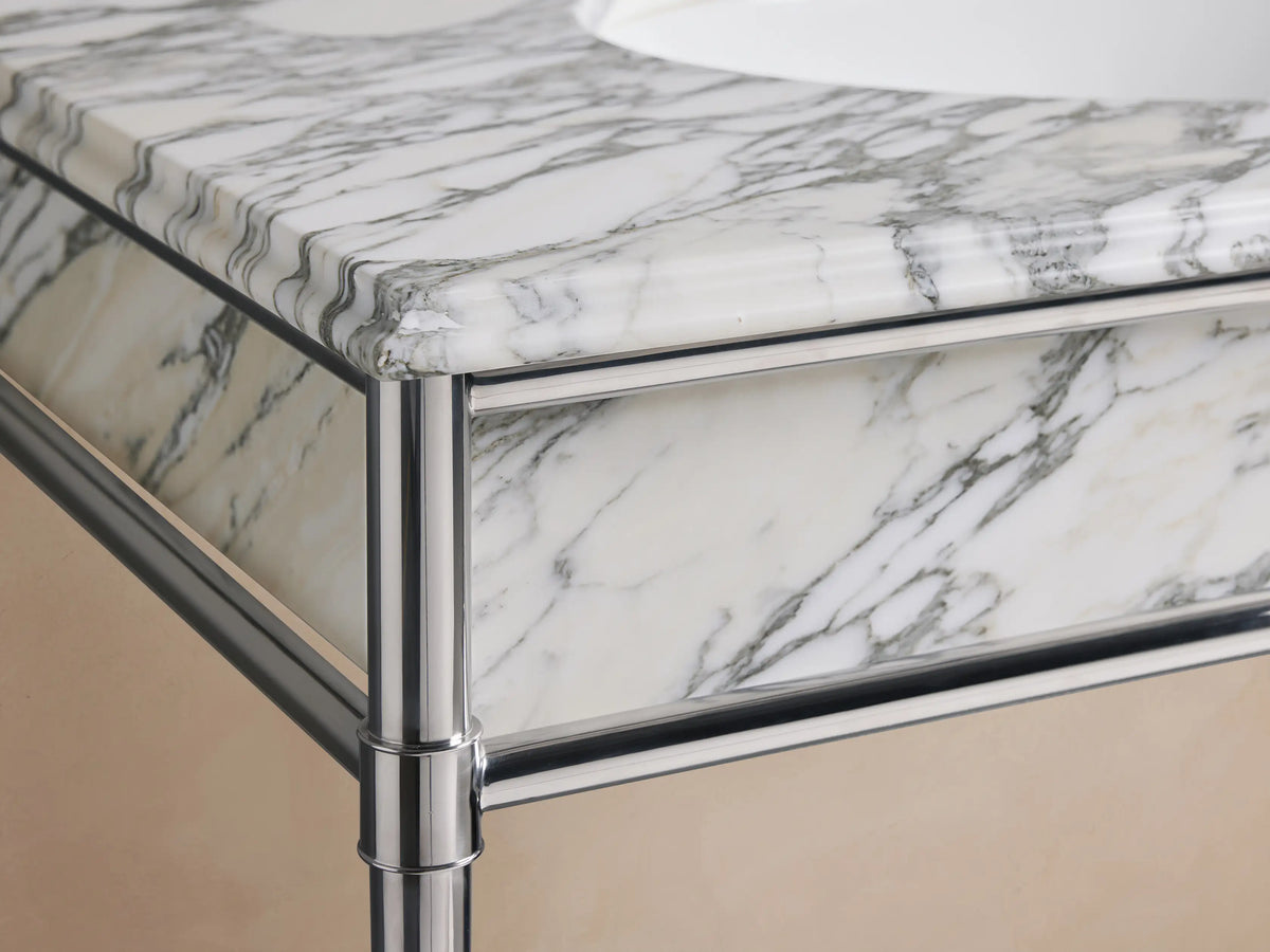 Chelsea Single Washstand close-up. White Carrara marble countertop with grey veining, oval white ceramic undermount sink, 3 faucet holes.