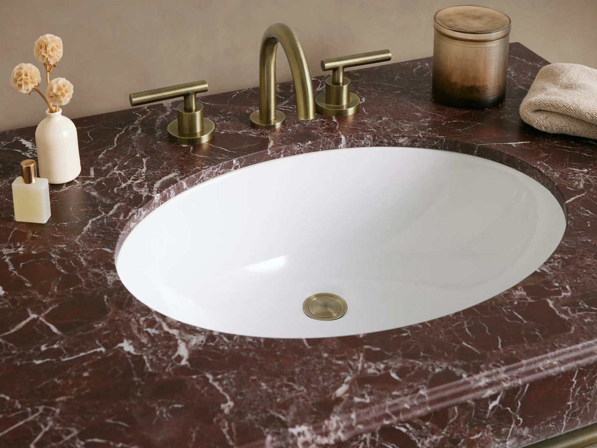 Chelsea Single Washstand with mottled red marble top, white oval sink, and antique brass frame with glass shelf, front view.