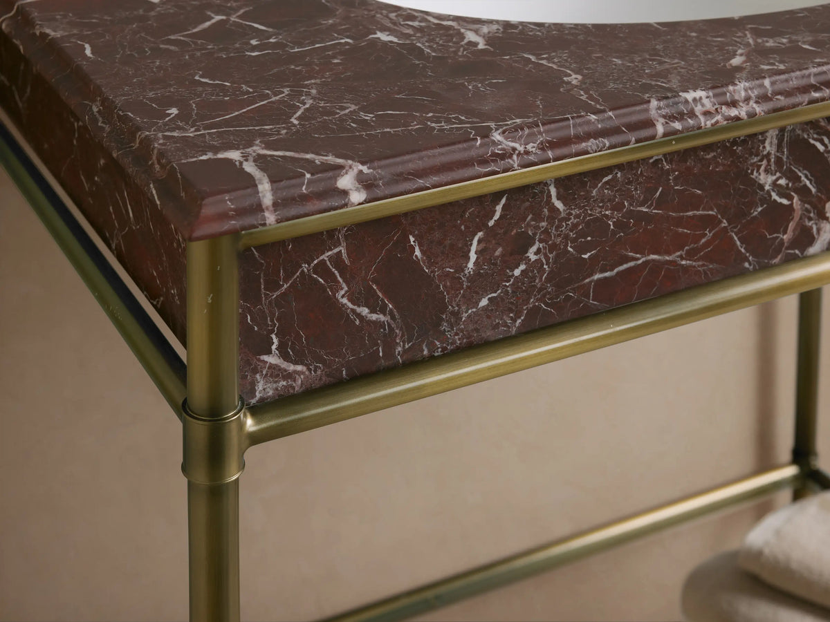 Chelsea Single Washstand close-up: Red Levanto marble countertop with white veining, white oval undermount sink, 3 faucet holes.