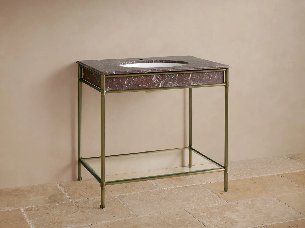 Chelsea Single Washstand with Red Levanto marble top, white oval sink, gold faucet, antique brass frame & glass shelf.