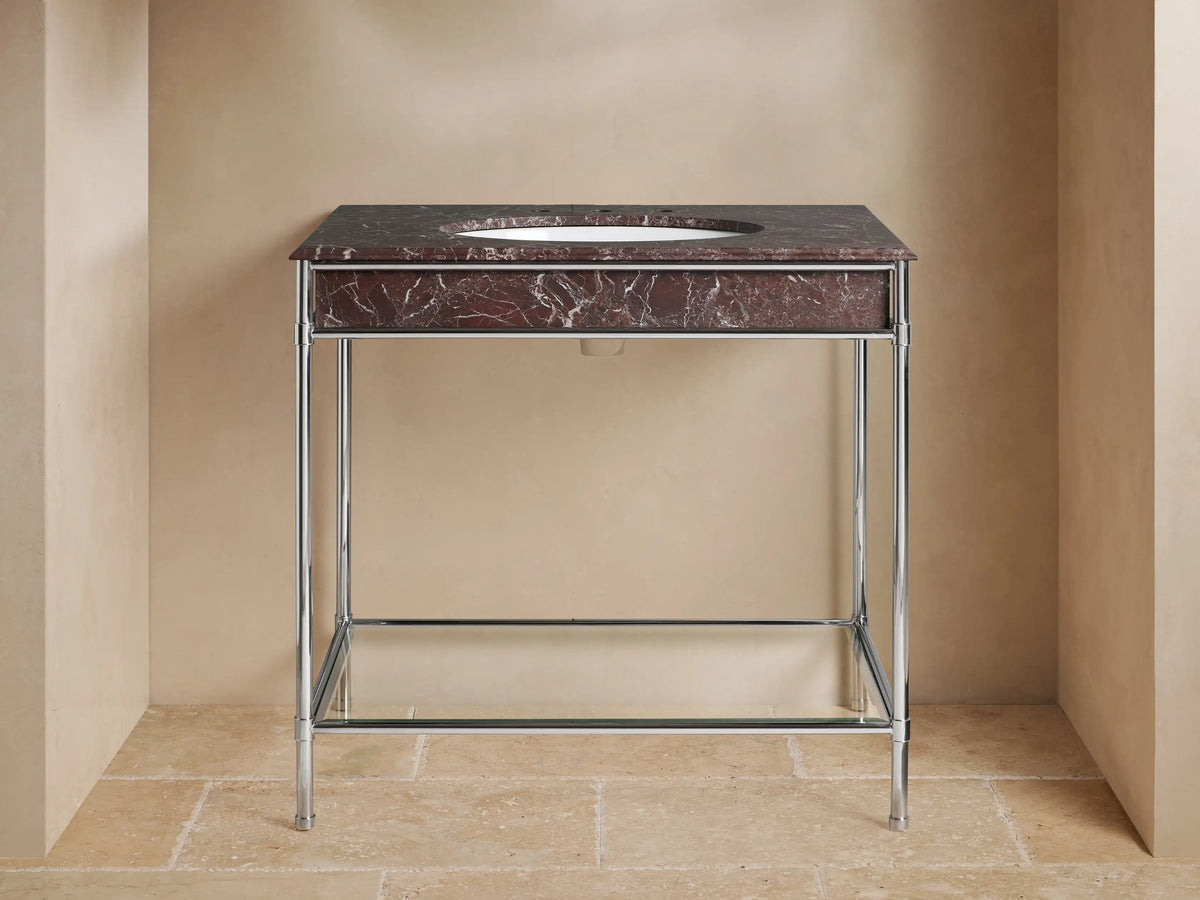 Chelsea Single Washstand: Dark red marble top, white oval sink, polished nickel frame, glass shelf with towels & vase.