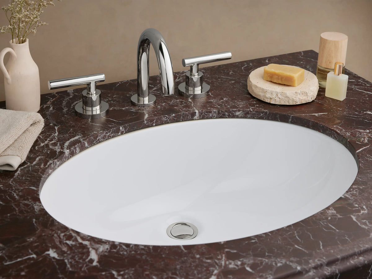 Chelsea Single Washstand. Polished chrome frame with a dark red Levanto marble top, white oval sink, & clear glass shelf.