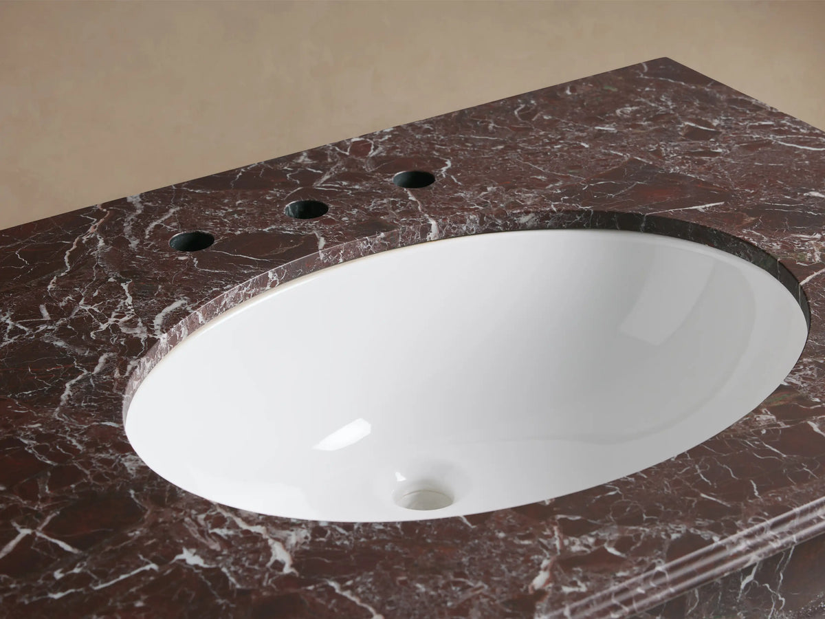 Close-up of Chelsea Single Washstand with a white oval undermount sink, dark Red Levanto marble top, and polished nickel faucet.