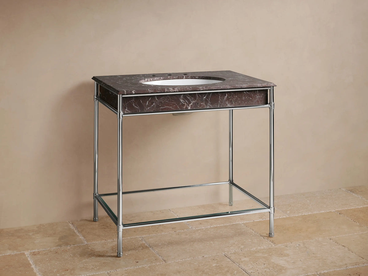 Chelsea Single Washstand with polished nickel frame, dark red marble top, white oval sink & chrome faucet against beige wall.