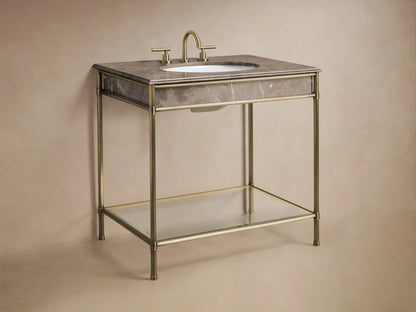Close-up of the Chelsea Single Washstand's glass shelf with an antique brass frame, holding folded beige towels.