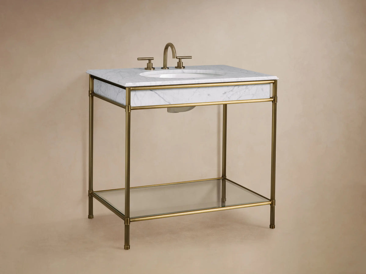 Close-up of Chelsea Single Washstand showing bronze frame, glass shelf with stacked beige towels, stone bowl, and tiled floor.