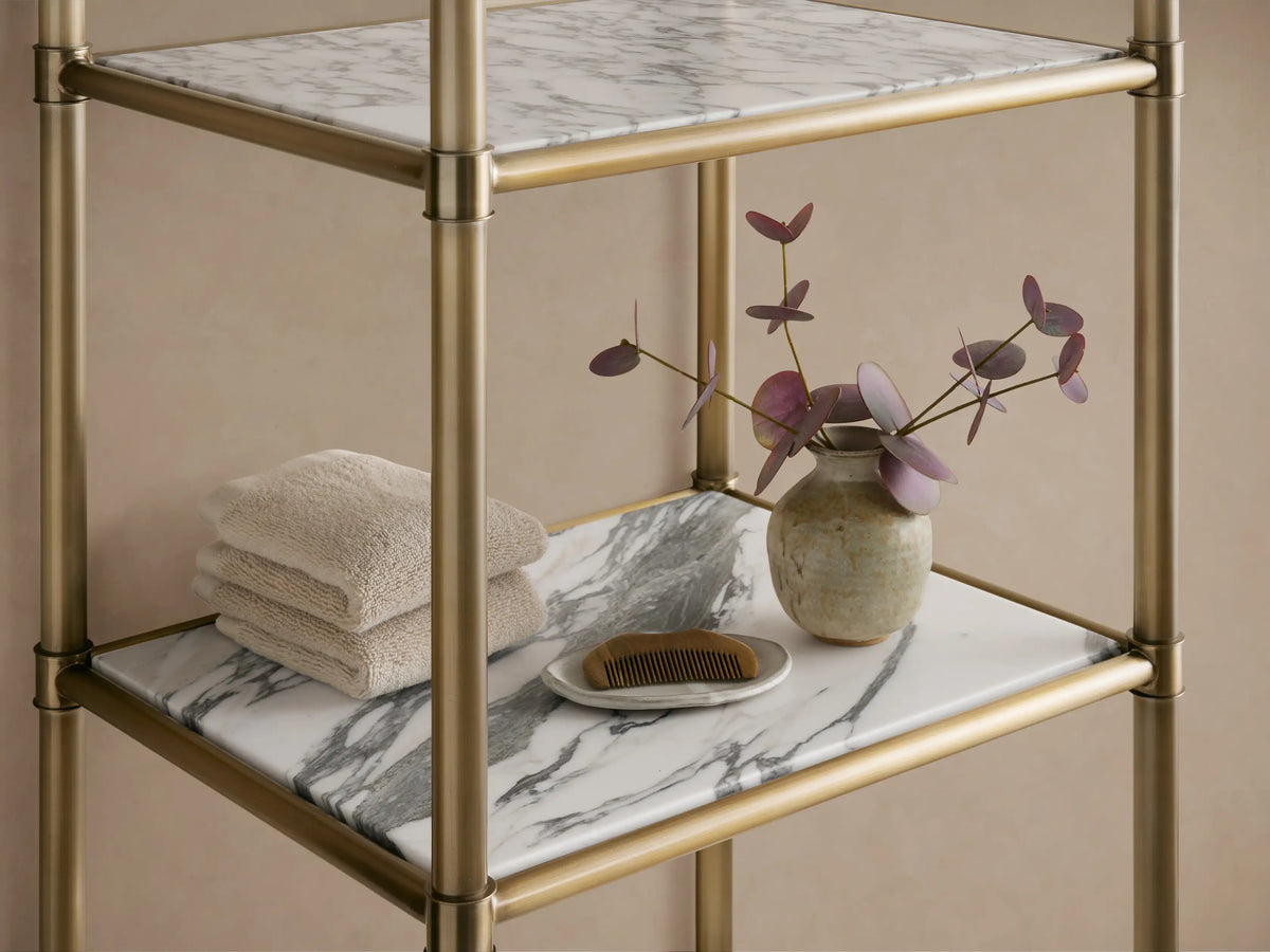 Chelsea Tall Etagere: 5-tier, antique brass frame with white marble shelves featuring grey veining, against a beige wall.