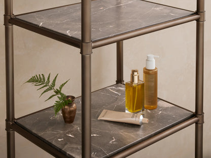 Chelsea Tall Etagere with an antique brass metal frame and five dark, patterned marble shelves, against a beige wall.