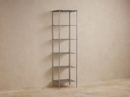 Chelsea Tall Etagere in polished nickel finish with five open shelves, stone top, displaying decor and rolled towels against a beige wall.
