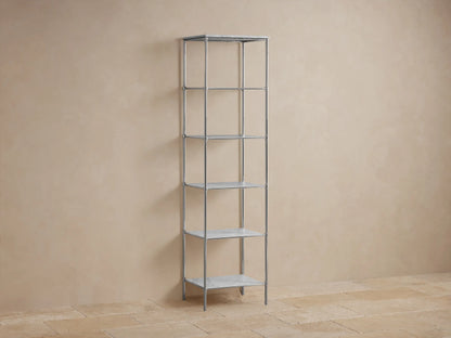 Chelsea Tall Etagere made of stainless steel in polished nickel finish, featuring five shelves with decorative items and towels, against a beige wall.