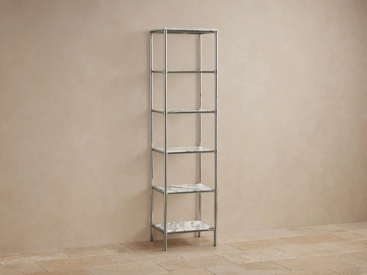Chelsea Tall Etagere, polished nickel frame, 5 veined marble shelves, displaying towels, bottles, vases in a beige room.