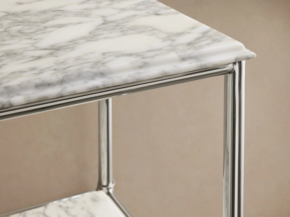 Chelsea Tall Etagere: Polished nickel frame with white marble shelves. Lower shelf has vase, dish, green towels, lit candle.