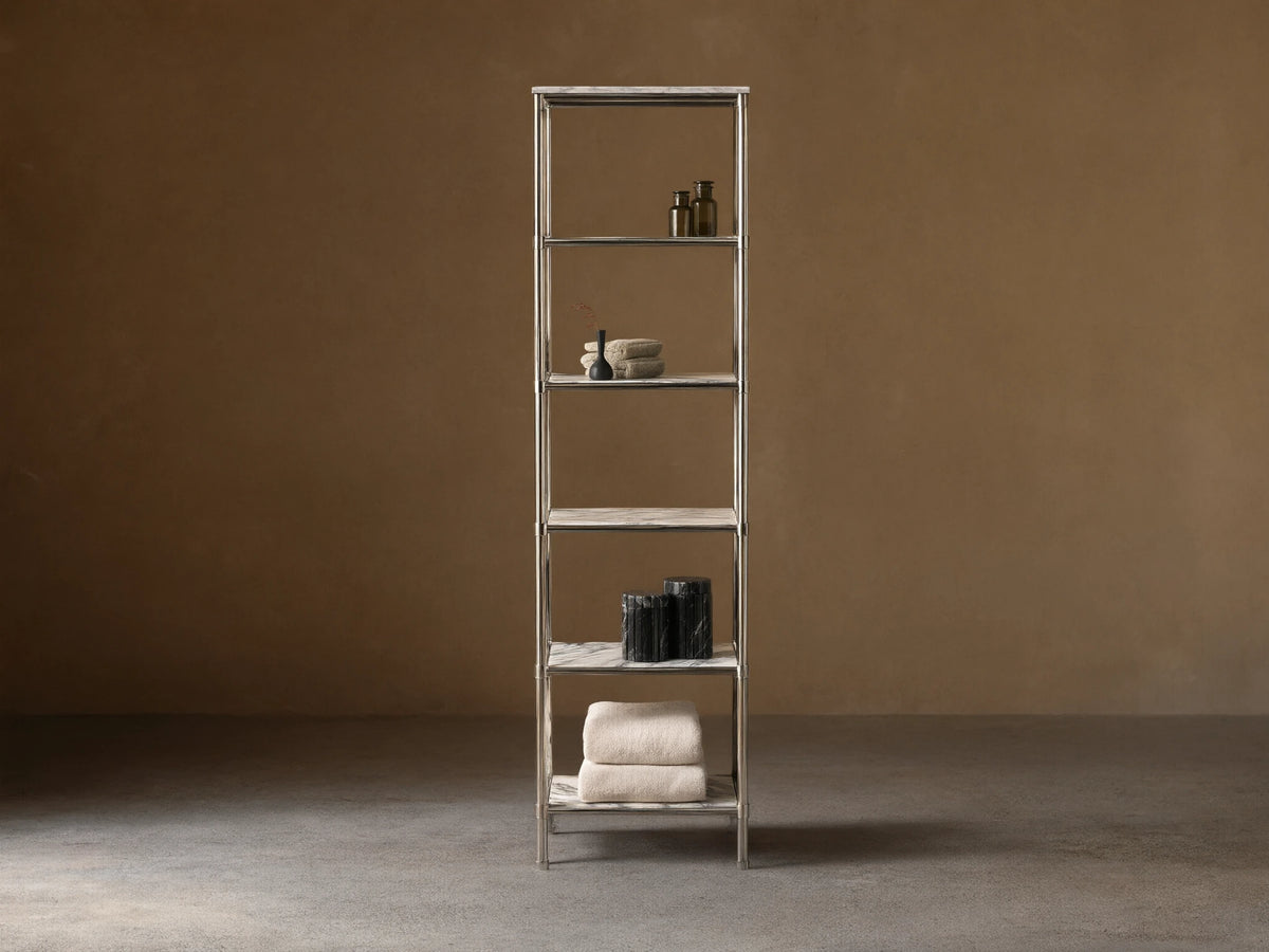 Chelsea Tall Etagere, polished nickel frame, 5 veined marble shelves, displaying towels, bottles, vases in a beige room.