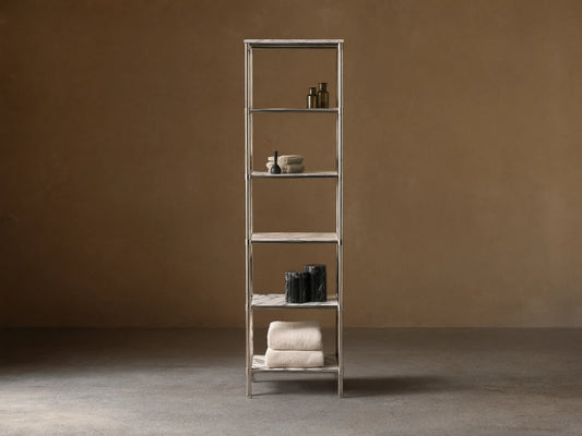 Chelsea Tall Etagere, polished nickel frame, 5 veined marble shelves, displaying towels, bottles, vases in a beige room.