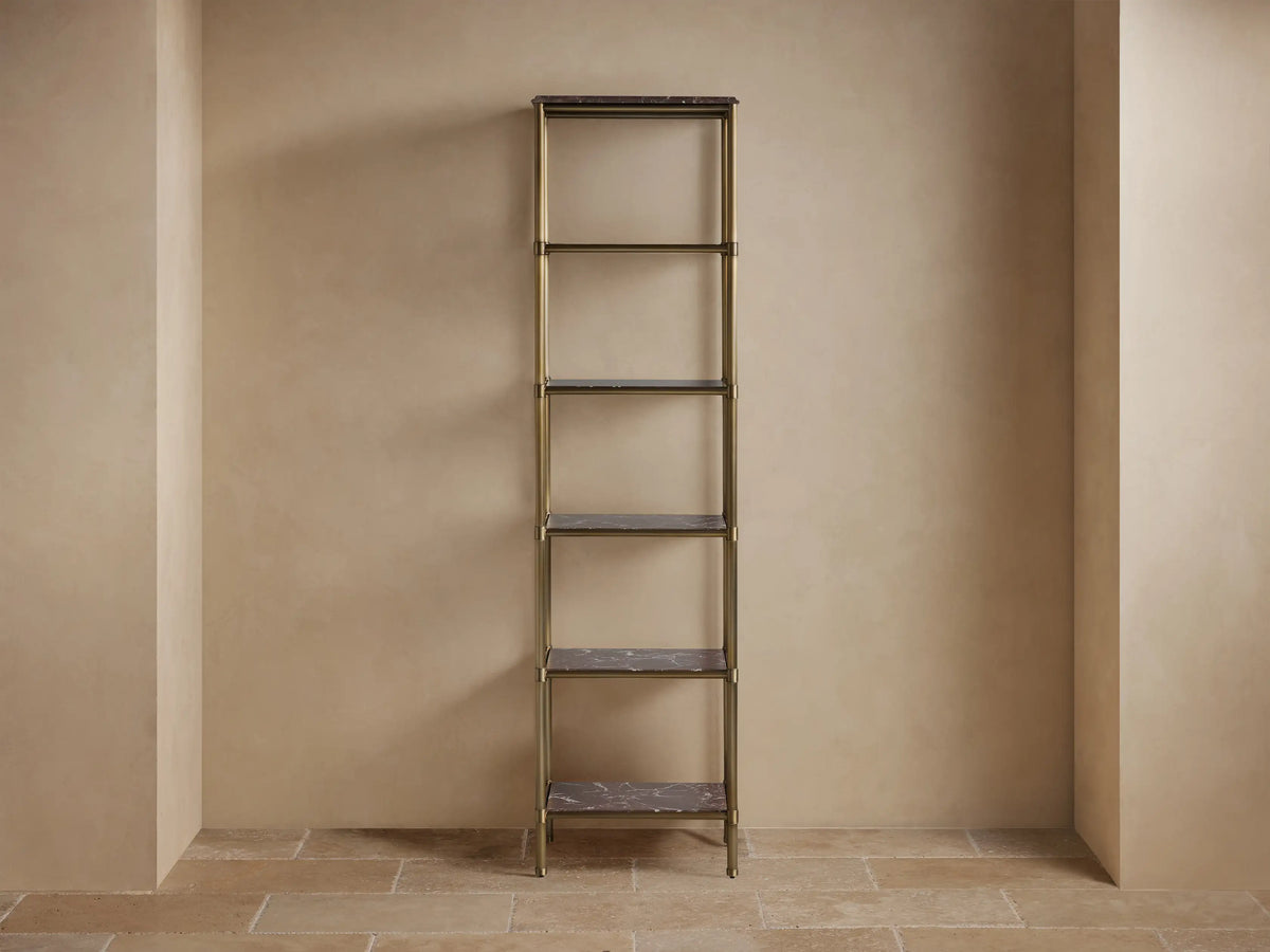 Chelsea Tall Etagere: antique brass frame, dark stone shelves. Decorated with bath items against a light wall and tiled floor.