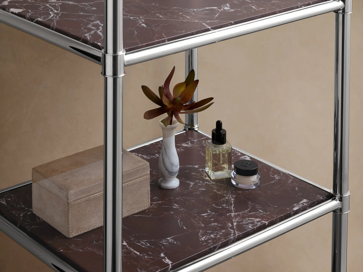 Chelsea Tall Etagere with polished nickel frame, five dark brown marble shelves, standing upright against a beige wall.