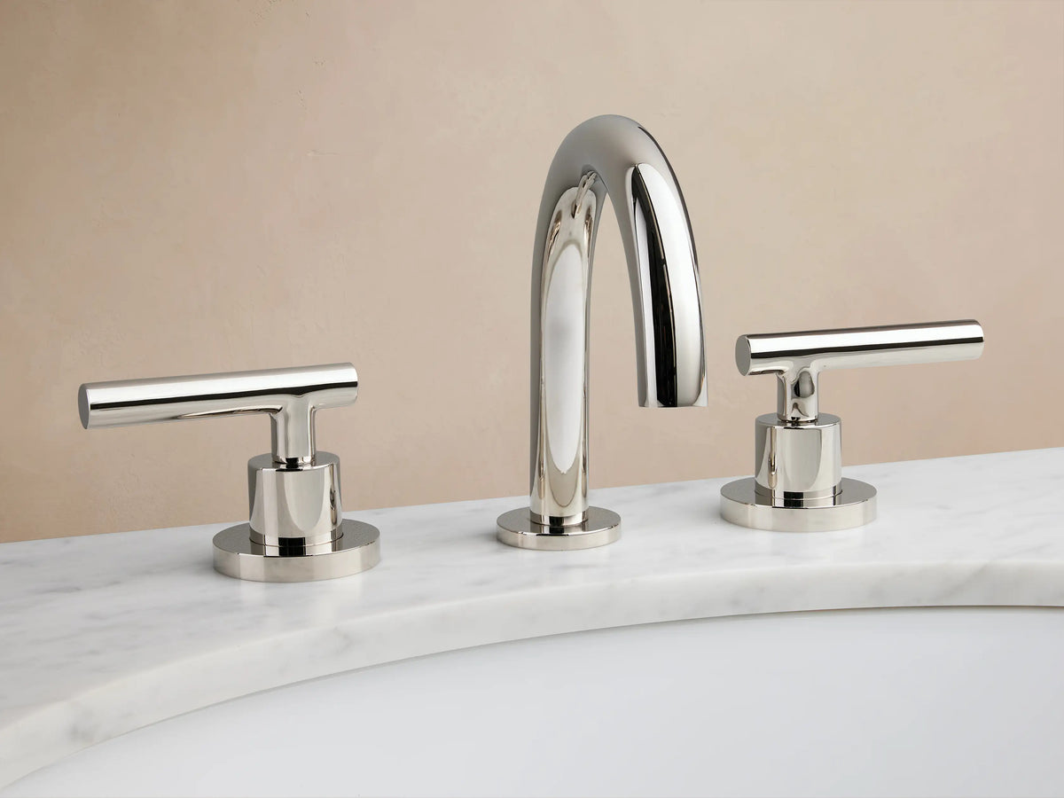 Polished nickel Crewe Smooth Faucet with curved spout and two cylindrical handles, mounted on a marble countertop.