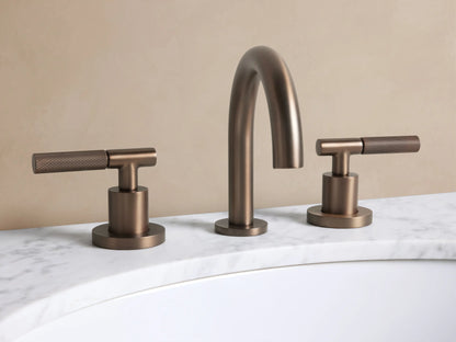 Crewe Knurled Faucet in Bronze: Three-piece widespread bronze faucet with a gooseneck spout & knurled T-handles on white marble.