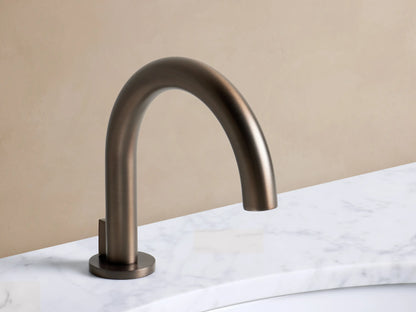 Crewe Knurled Faucet in Bronze with high-arc spout and two knurled handles on a white marble counter with a white sink.
