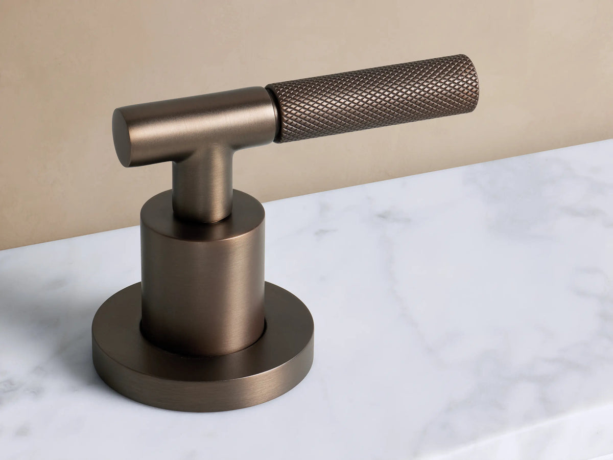 Crewe Faucet: Arched antique bronze spout with round base, mounted on a white marble countertop.
