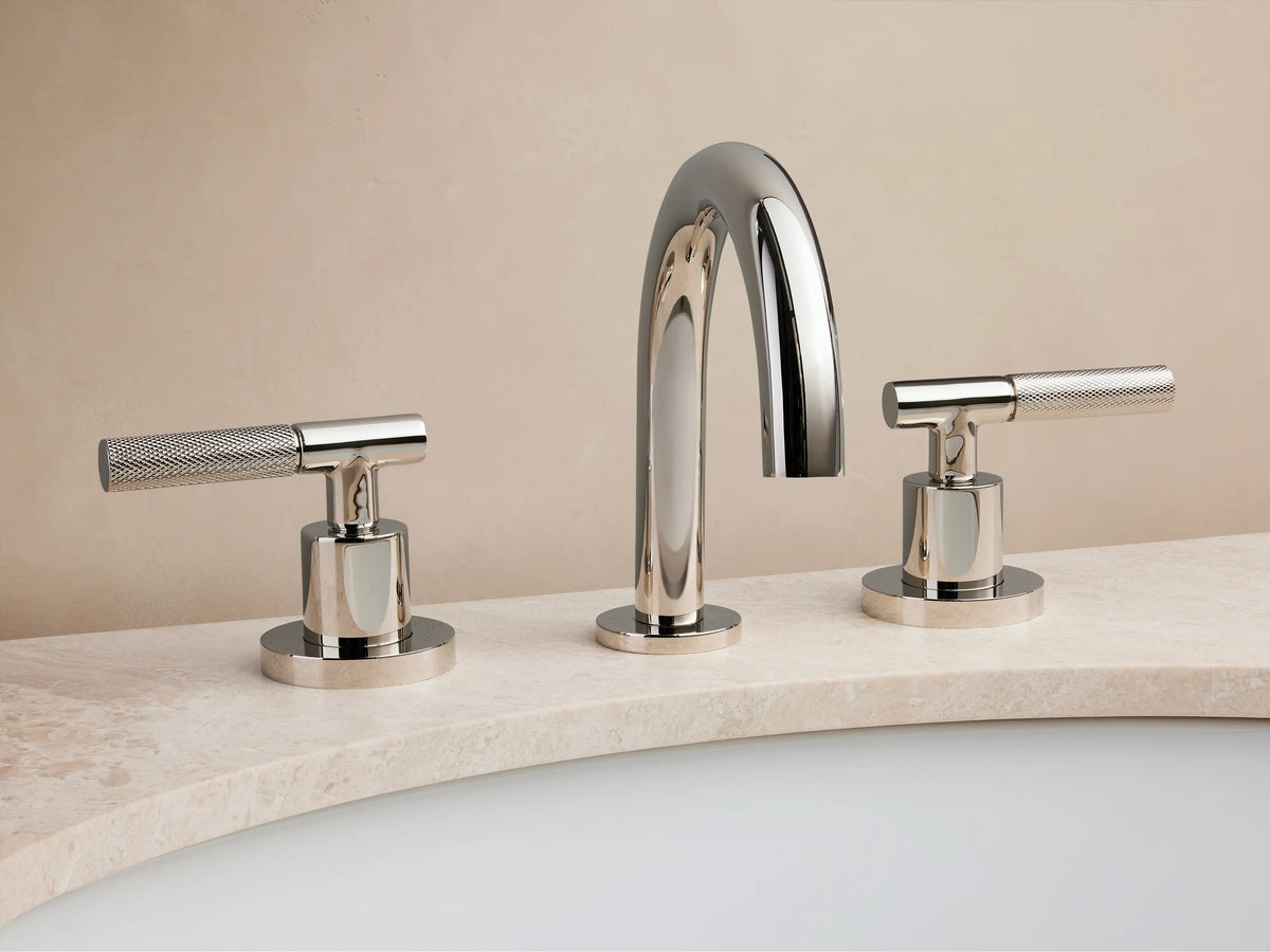 Crewe Knurled Faucet in polished nickel with curved spout and two textured handles on marble countertop, set against a beige background.