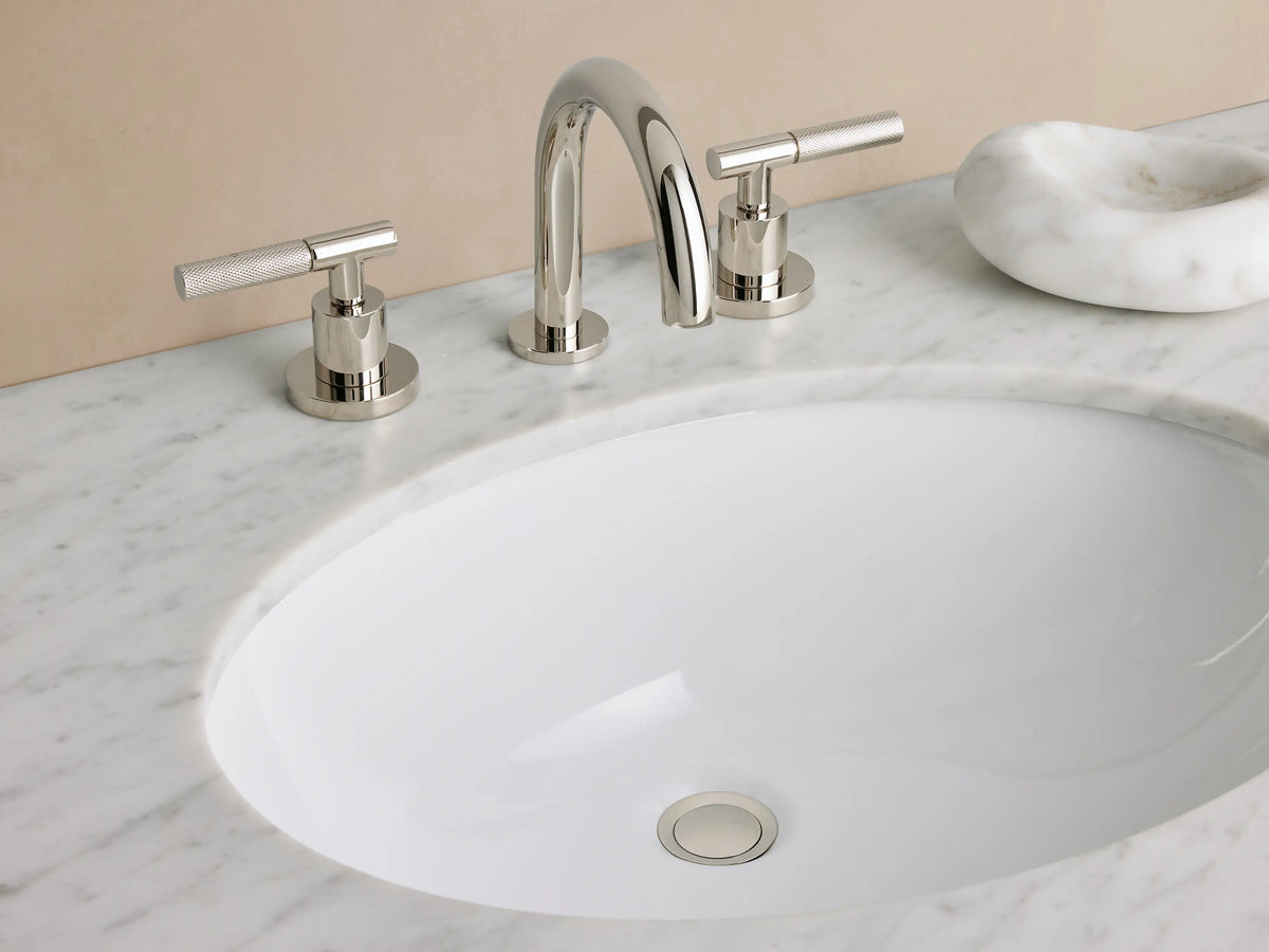 Crewe Knurled Faucet pop-up drain in polished nickel, circular design with a smooth, reflective surface, set in white countertop.