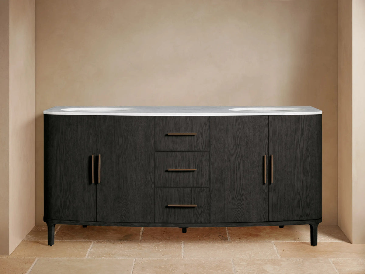 Danny Double Vanity: Dark black oak vanity with white marble top, two sinks, brass faucets. Left door slightly open showing towels.