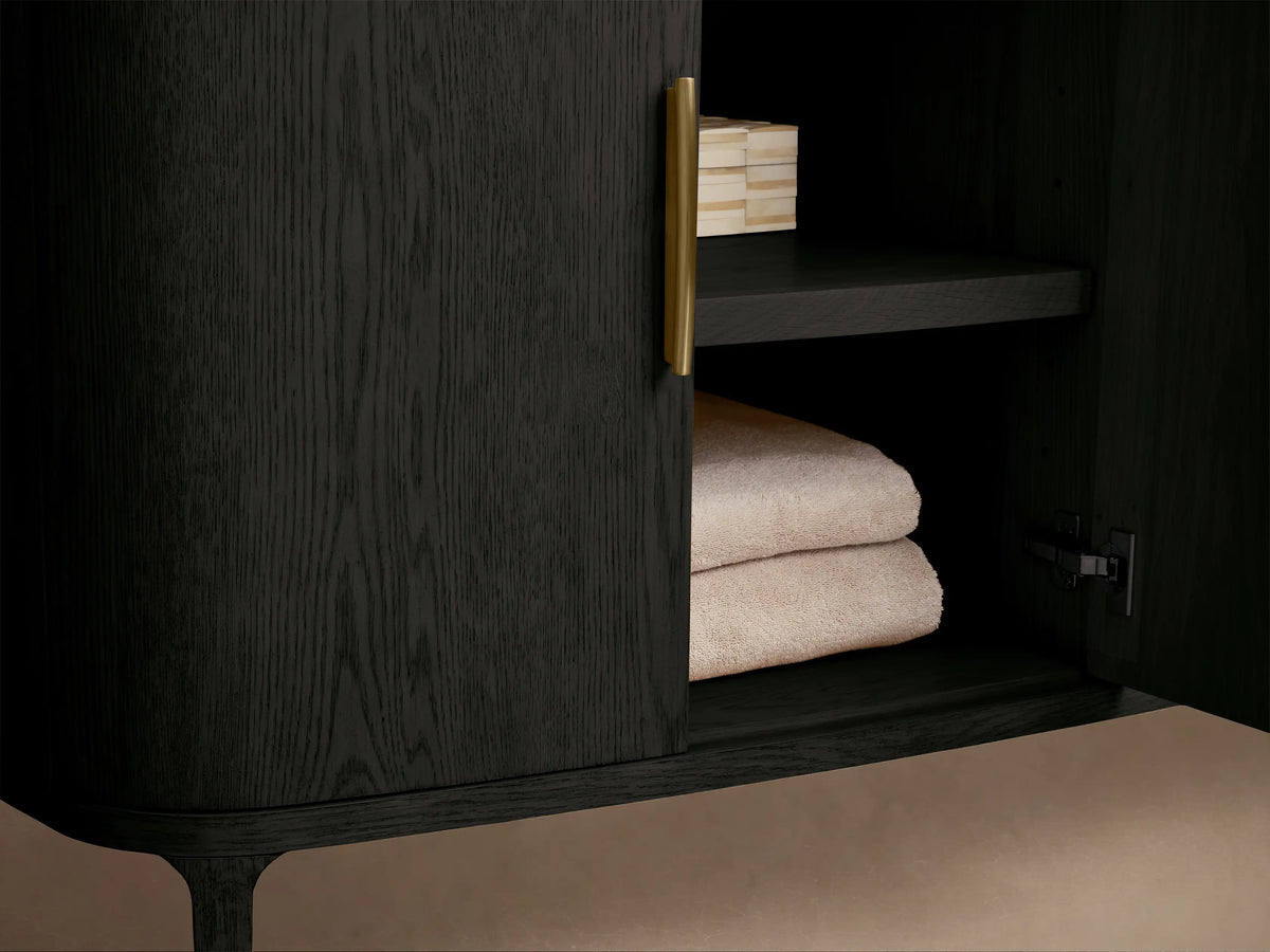 Close-up of black oak Danny Double Vanity. White marble top. Drawer partially open with beige towels, antique brass pull handle.