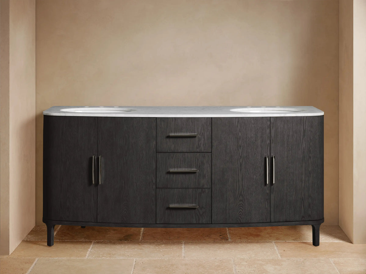 Danny Double Vanity in dark oak wood with two sinks and smooth marble top. Open cabinet showing storage, flanked by mirrors.
