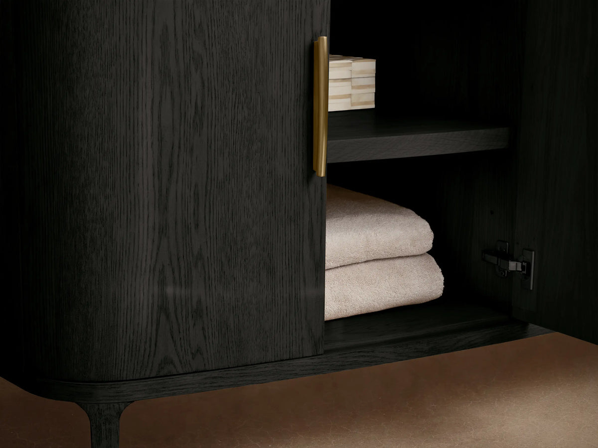 Close-up of Danny Double Vanity: black oak finish cabinet, brass handles. Partially open drawer with folded towel. Light marble top.