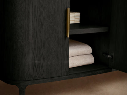Close-up of Danny Double Vanity: black oak finish cabinet, brass handles. Partially open drawer with folded towel. Light marble top.