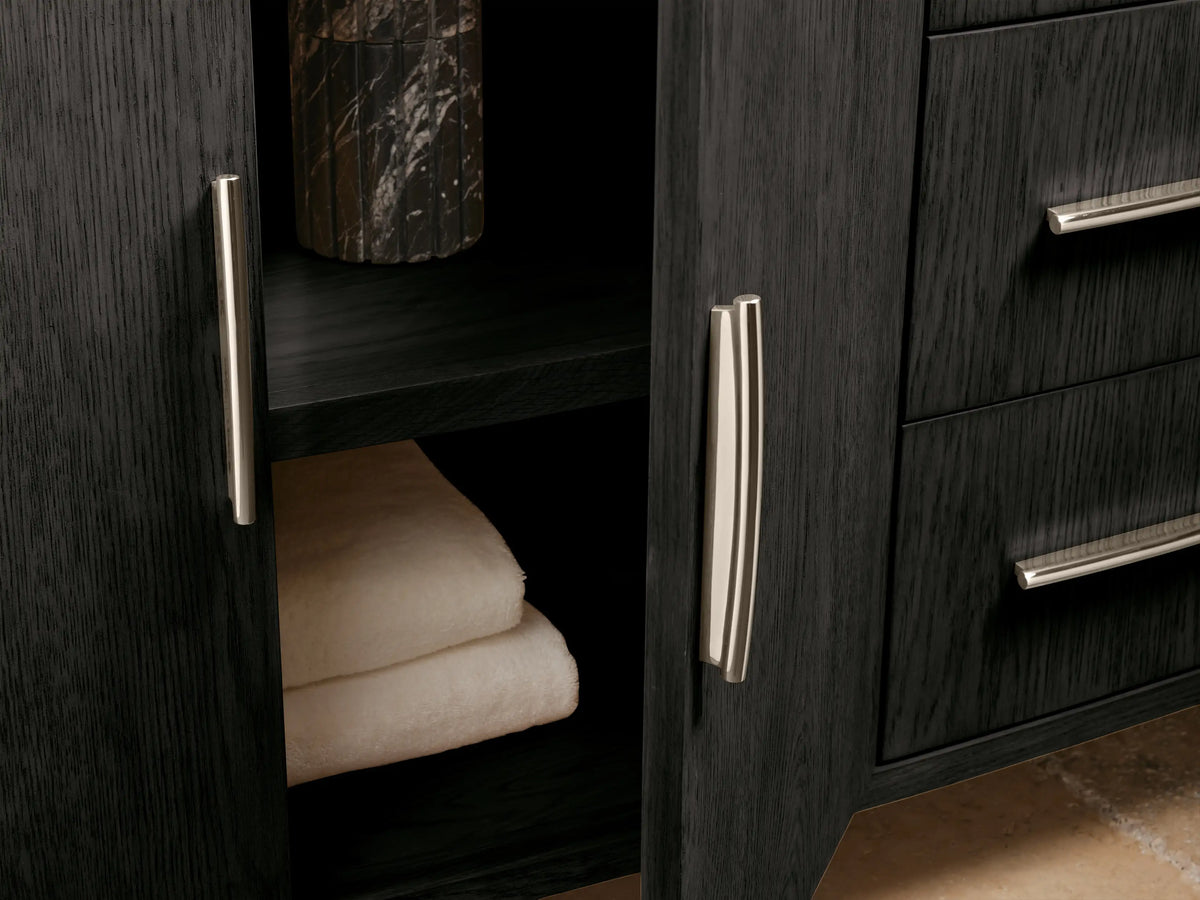 Close-up of Danny Double Vanity. Dark textured wood cabinet with light cream marble top. Drawer open, revealing a white towel; silver handle visible.