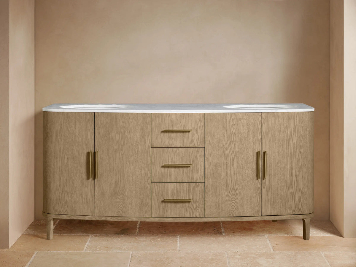 Danny Double Vanity made of oak wood with brass hardware, two sinks, and a marble top. Features multiple drawers and open shelves.