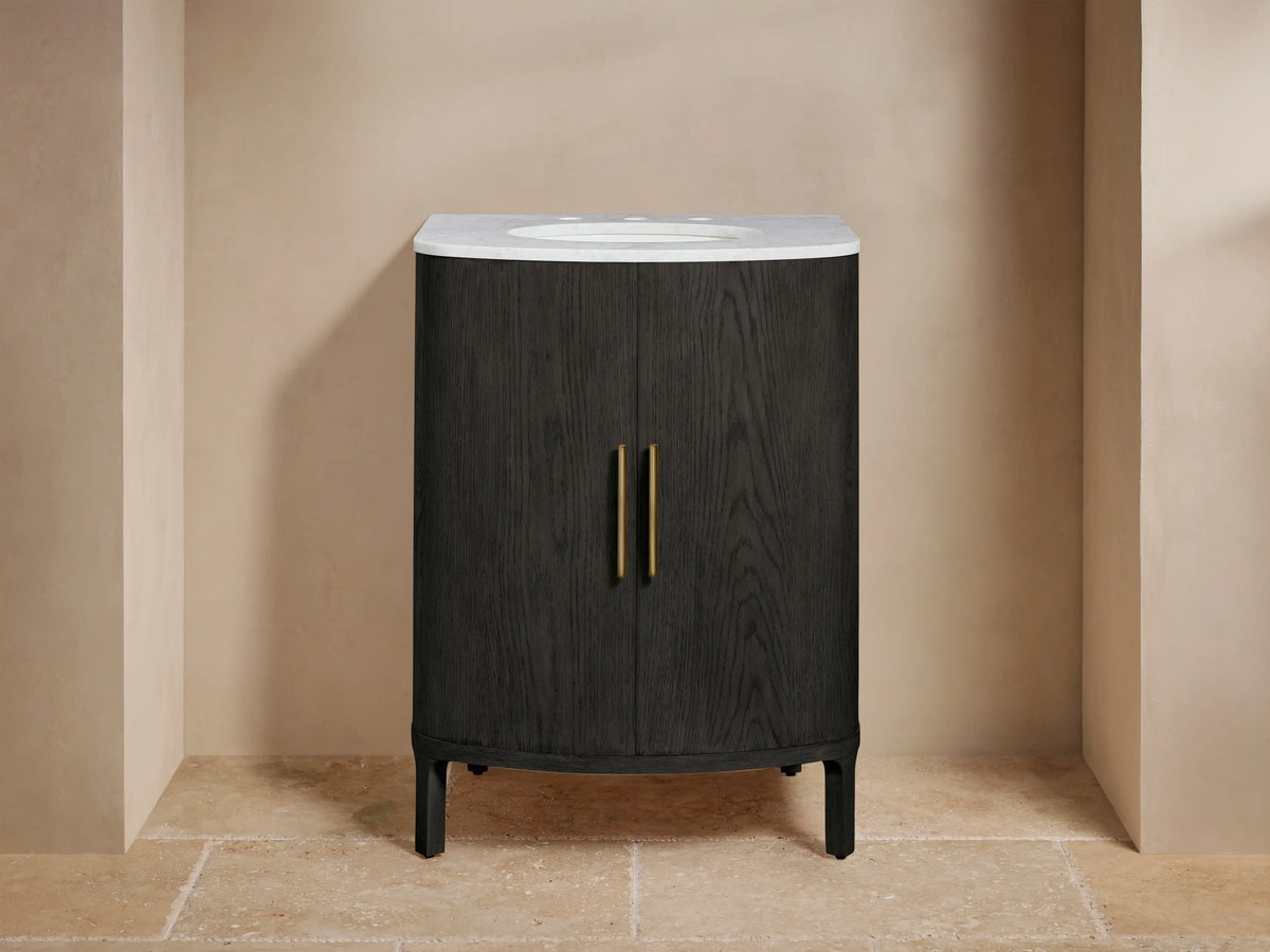 Close-up of Danny Powder Vanity's open black oak door, showing wood grain, brass handle, curved shelves, and folded towels.