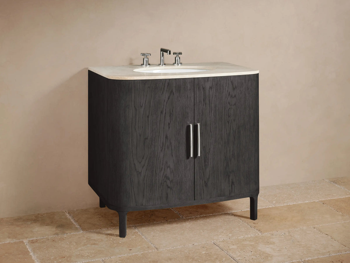 Open Danny Single Vanity cabinet in dark oak showing two shelves. Towels and a marble box on top shelf, dark container on bottom shelf. Chrome handle on left door.