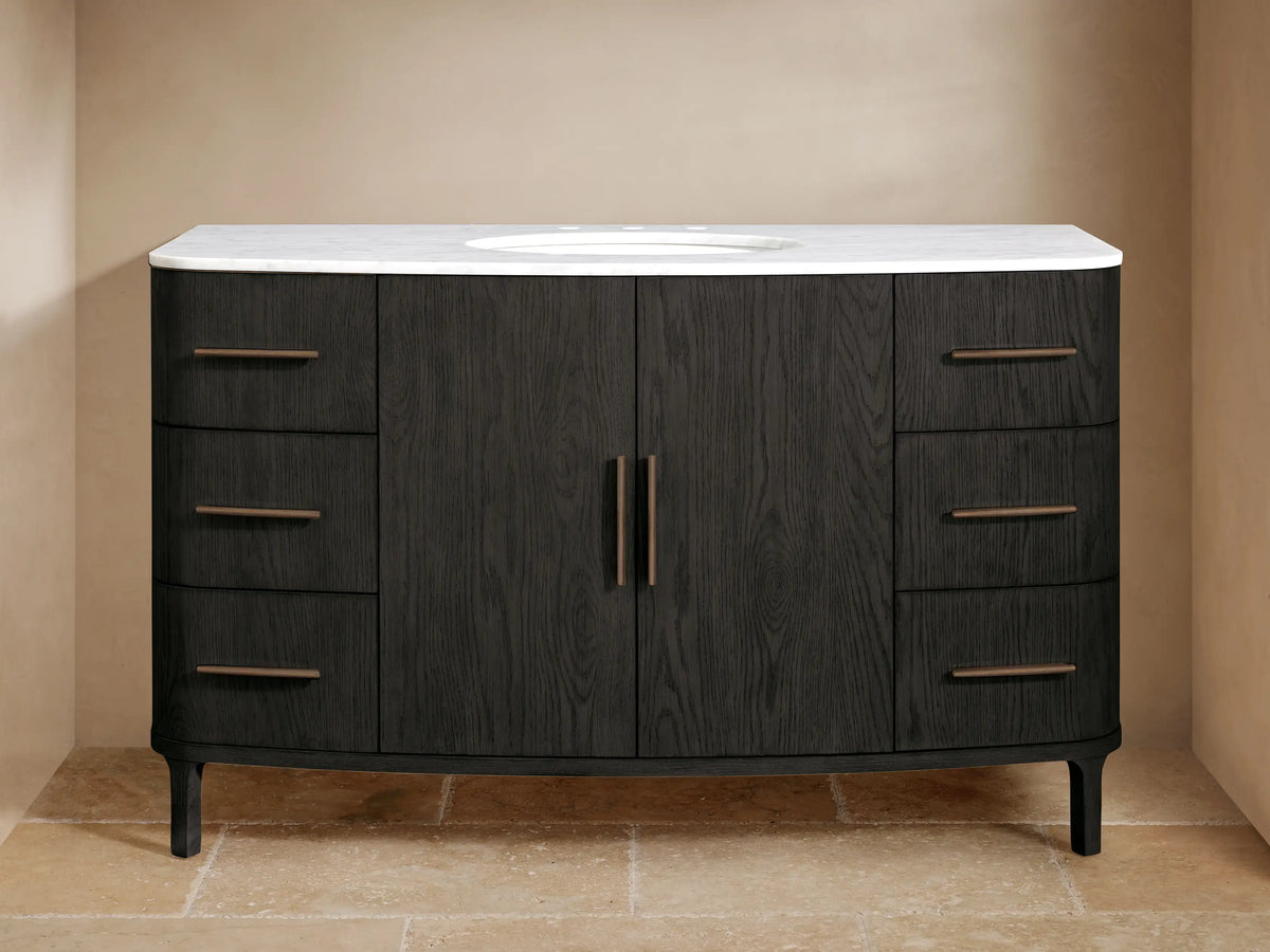 Danny Wide Single Vanity, dark oak, white Carrara marble top, oval sink, bronze hardware, three drawers each side.