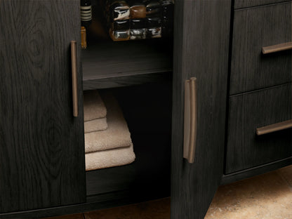 Dark oak Danny Wide Single Vanity with curved edges. White marble top, bronze handles. Open drawer reveals a folded beige towel.