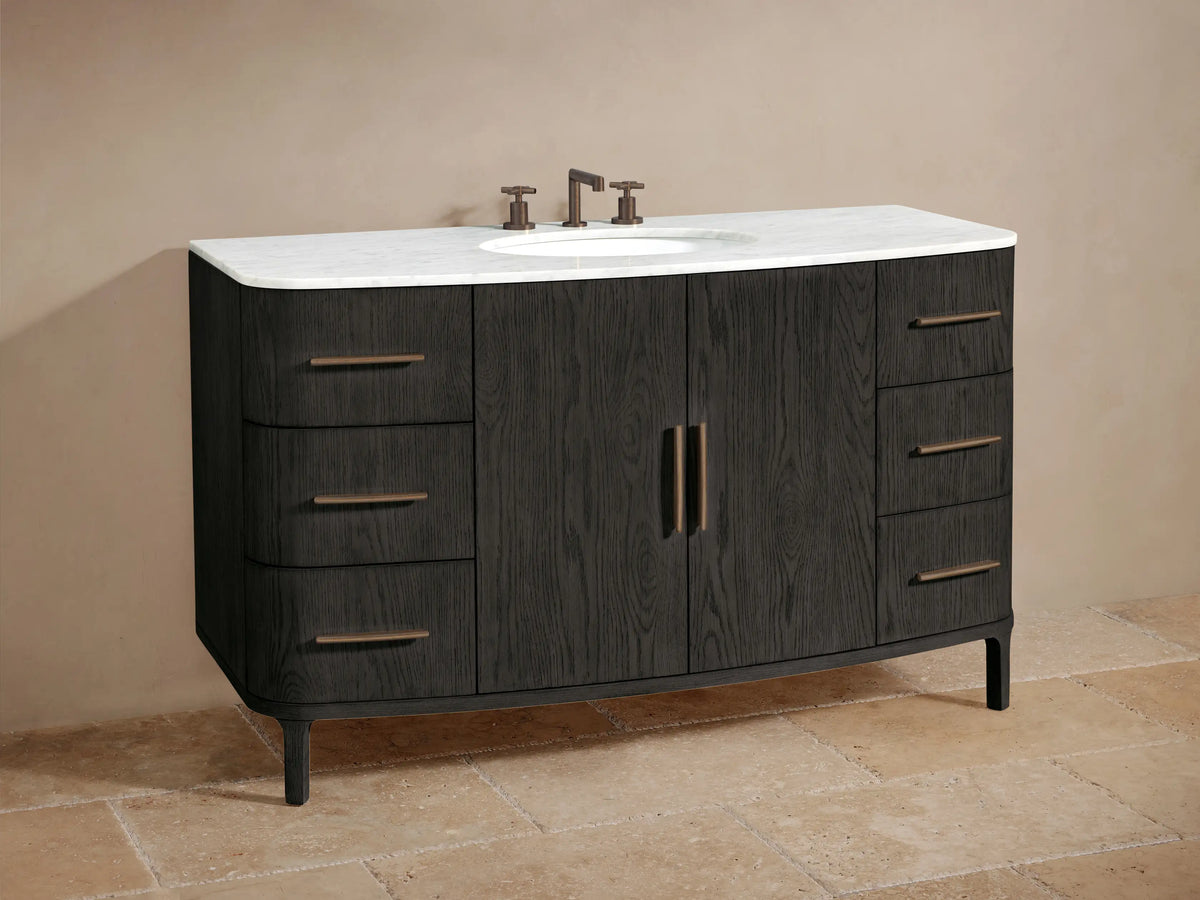 Dark oak Danny Wide Single Vanity with open cabinet door showing towels & bottles on shelves. Bronze handles on door & drawers.