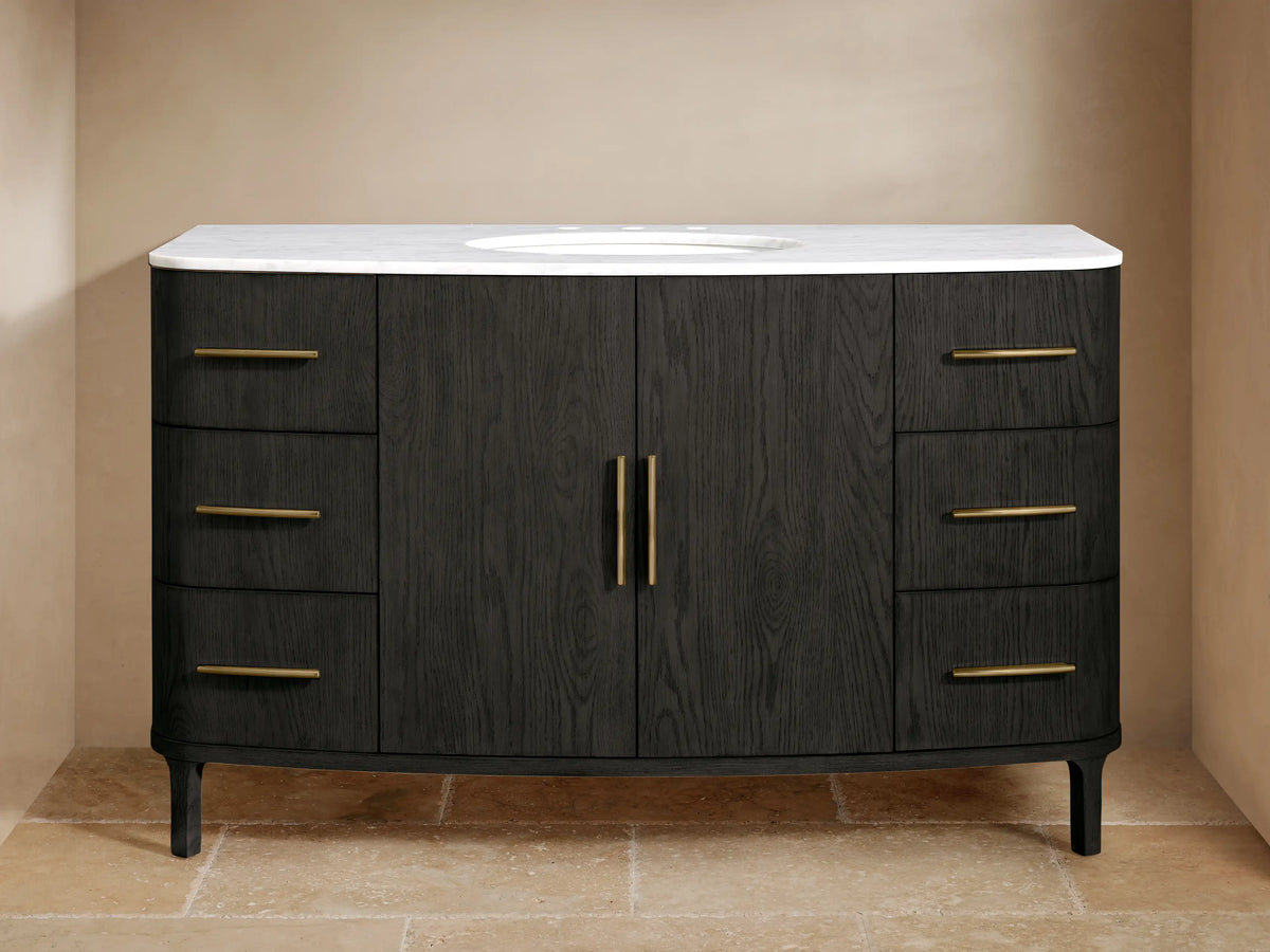 Black oak Danny Wide Single Vanity, curved, with white marble top, oval sink, and brass hardware. Six drawers & two doors.