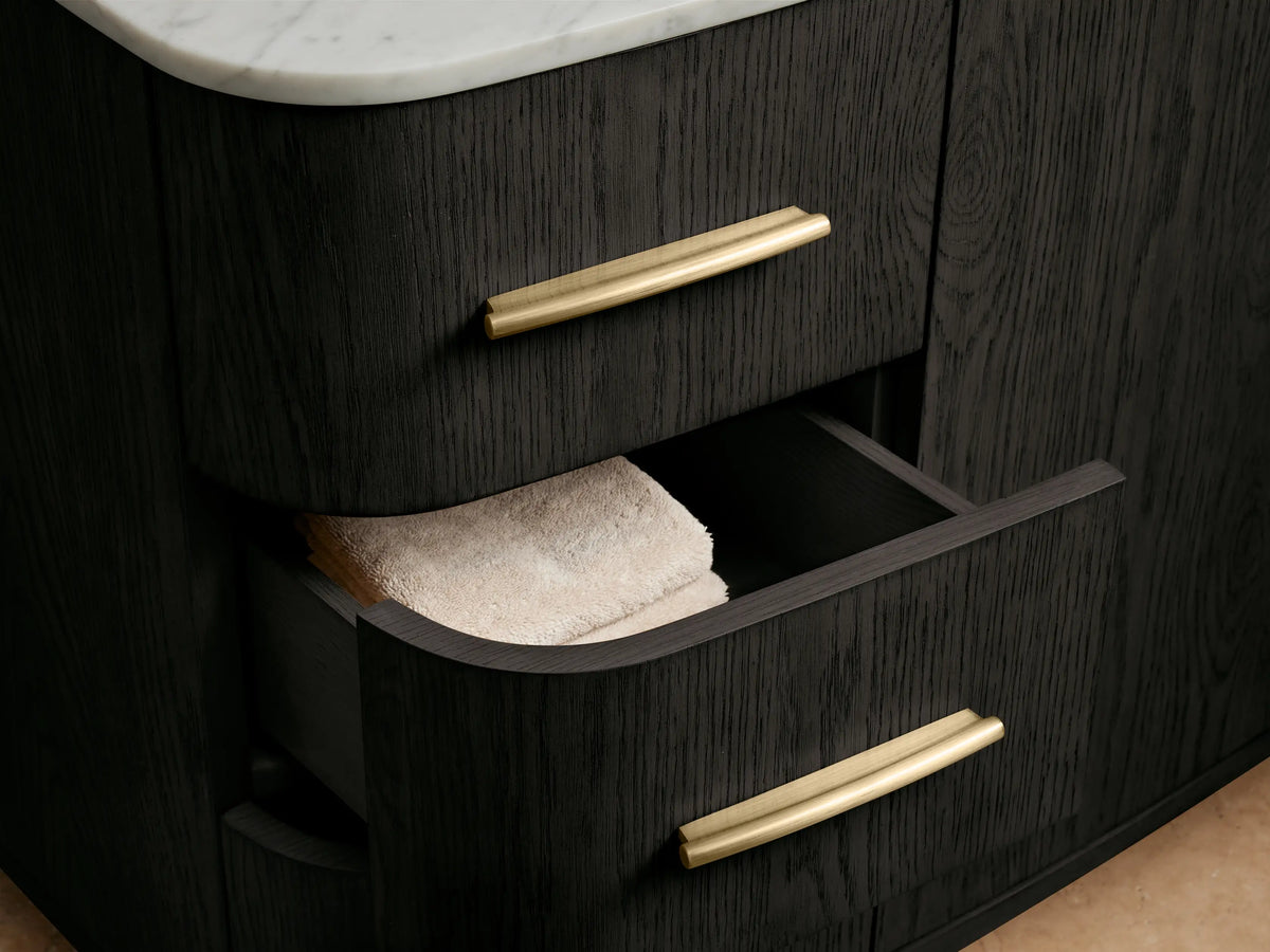 Danny Wide Single Vanity: White oval sink, Carrara marble top with brass widespread faucet, brass drain, dark cabinet below.
