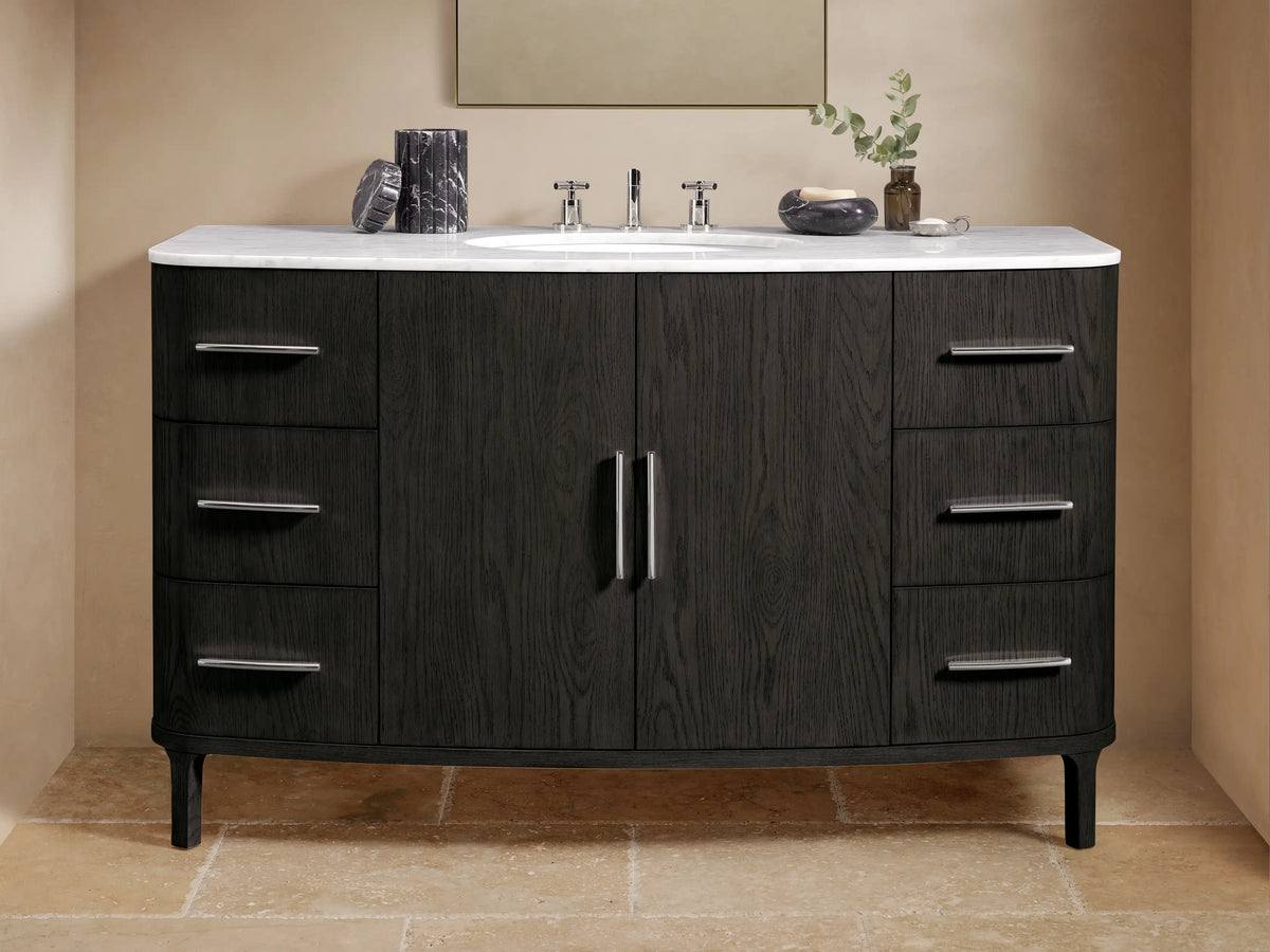 Danny Wide Single Vanity: Dark oak wood with prominent grain, white Carrara marble top, oval sink, polished nickel handles.