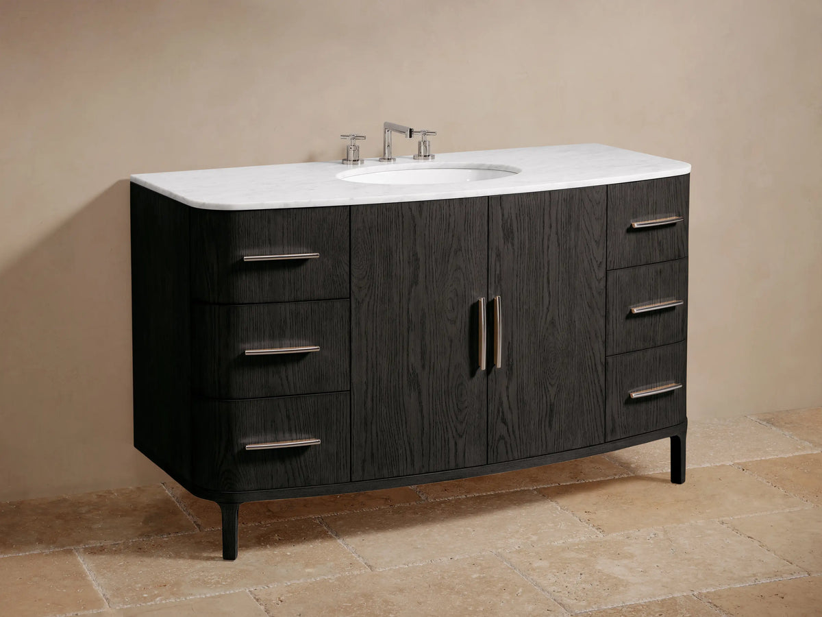 Danny Wide Single Vanity: close-up of dark oak cabinet, white marble top. Curved bottom drawer open with gray towels, silver pull.
