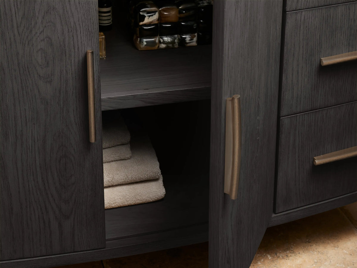 Close-up Danny Wide Single Vanity in charcoal oak with light stone top & bronze handles. Bottom drawer open, holding folded light towel.