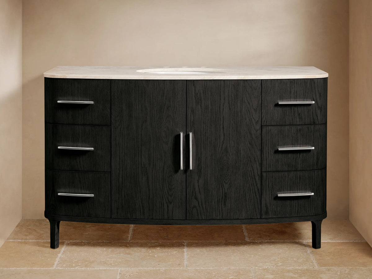 Danny Wide Single Vanity: dark oak, curved front, white marble top with oval sink, polished nickel hardware. On tiled floor.