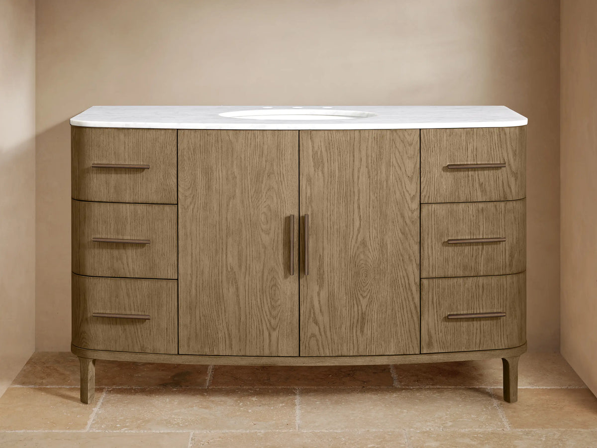 Danny Wide Single Vanity in light brown oak wood with a white marble top and oval sink. Features 2 central doors and 6 drawers with bronze pulls.