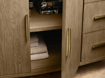 Oak wood Danny Single Wide Vanity with curved front design, featuring open drawer revealing a folded towel, gold-colored handles, and marble top edge.