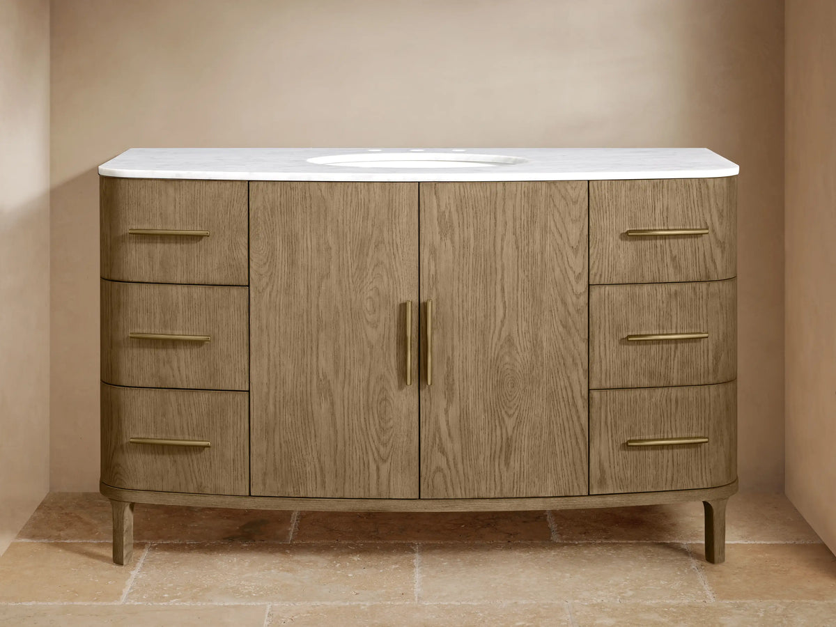 Danny Single Wide Vanity in oak with open cabinet doors showing shelves, towels, and toiletries; Antique Brass hardware.