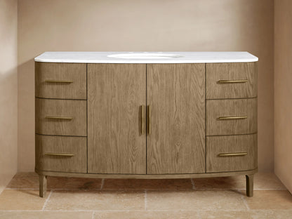 Danny Single Wide Vanity in oak with open cabinet doors showing shelves, towels, and toiletries; Antique Brass hardware.