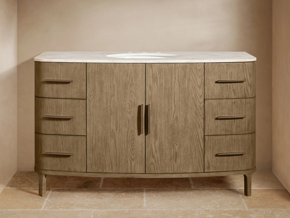 Light brown oak wood Danny Wide Single Vanity with a white marble top, oval sink, and dark bronze hardware. Six drawers, two central doors.